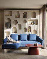 Blue corner sofa in front of sculpted storage shelves