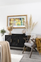 Wall mounted television with art image above a sideboard in a modern living room