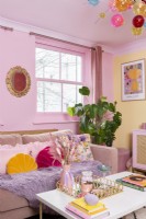 Corner of colourful living room with pink sofa and coffee table
