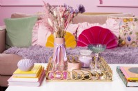 Detail of tray with accessories on a coffee table in front of colourful sofa
