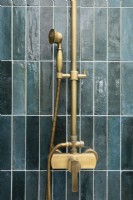 Brass shower fixtures on green tiled shower unit