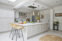 Modern kitchen with grey shaker-style cabinets. Large island with pendant lights and a bar.