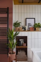 Bathroom detail with black towel rail, white tiles and a pink painted wall.