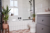 Bathroom with colourful vinyl flooring, black fittings, white tiles and a grey under sink cupboard.