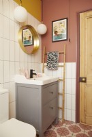 Bathroom with colourful vinyl flooring, white tiles and yellow and pink painted walls.