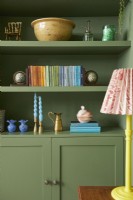 Living room detail with green painted shelving and yellow table lamp.