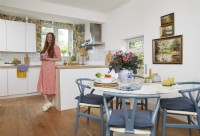 Open-plan kitchen and dining area with wooden floorboards, botanical wallpaper and vintage oil paintings.