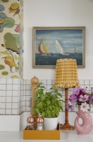 Kitchen detail with lamp, oil painting, white tiles and botanical wallpaper.