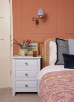 Bedroom detail with terracotta panelling and painted bedside cabinets.