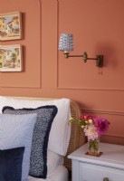 Bedroom detail with terracotta panelling, textured blue cushions and wall mounted vintage lights.