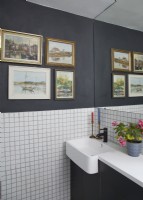 Bathroom detail with square white tiles, grey walls and vintage oil paintings.