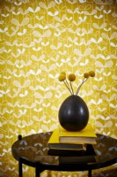 Vase and flowers in front of yellow wallpaper