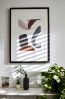 Picture and vases against white wall with shadows