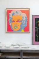 Colourful painting of Marilyn Munroe above table of white ceramics