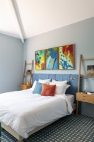 Colourful  artwork above bed in modern bedroom 