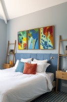 Colourful artwork above bed in modern bedroom