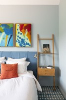 Colourful artwork above bed in modern bedroom
