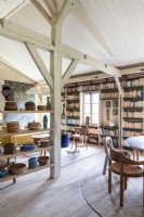 Exposed beams and shelves of ceramics in country reading room