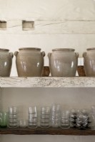 Detail of large ceramic pots and glassware on rustic shelving