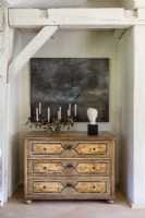 Large artwork above antique chest of drawers