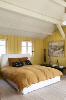 Modern country bedroom with yellow painted wooden walls