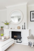 Round mirror and white painted brick fireplace in a modern neutral living room