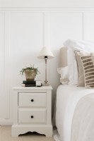 Detail of bedside chest of drawers against white paneled wall