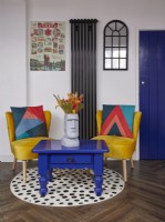 Seating corner with yellow chairs, a blue coffee table and a round spotty rug.
