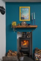 Living room detail of wood burner stove with teal blue painted wall.
