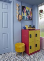 Blue painted entrance hall with yellow and pink lockers and a tiled floor.