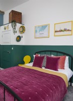 Bedroom with a green painted wall and purple bedding.