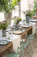 Rustic outdoor dining table laid for lunch with flower arrangments