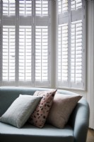 Detail of sofa and cushions with white shutters