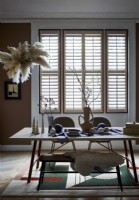 Dining table with ornaments and shutters at window