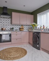 Kitchen with pink cabinets, green walls and patterned tiles.