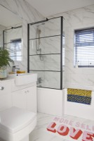 Bathroom with marble tiling and a crittall shower screen.