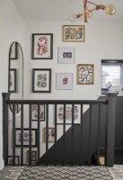 Gallery wall detail with black painted bannisters and a patterned rug.