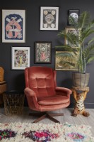 Living room detail with a retro armchair, tiger plant table and a gallery wall of illustrations.