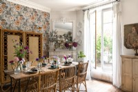 Eclectic dining room with patterned wallpaper and French windows