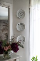 Display of wall mounted decorative plates next to mirror