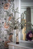 Flower arrangement and floral wallpaper next to mirror - detail
