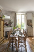Dining table and wicker chairs next to open French windows