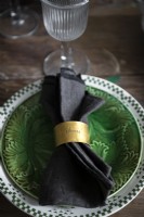 Gold napkin ring on serviette - vintage plates on dining table