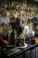 Detail of black kitchen counter and gold wallpaper