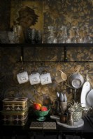 Detail of black kitchen worktop with gold embossed wallpapered wall