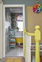 View from landing through to colourful bathroom with yellow freestanding bath, white metro tiles and grey walls.