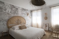 Modern country bedroom with bare plaster wall and rattan headboard