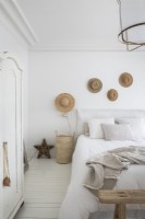 Display of straw hats on white country bedroom wall