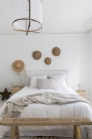 Display of straw heads above bed in white country bedroom