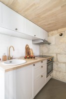 Small modern kitchen with exposed stone wall and wooden ceiling